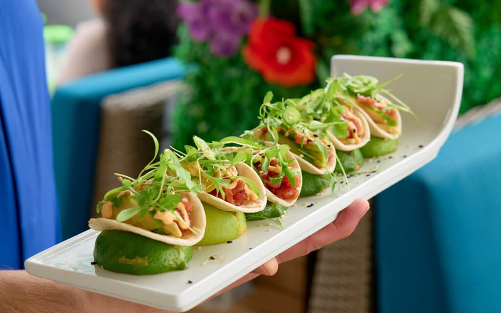 A tray of delicious soft tacos filled with fresh ingredients over individual limes